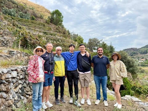 Group of seven people standing together on a hillside path with terraced vineyard landscape in background
