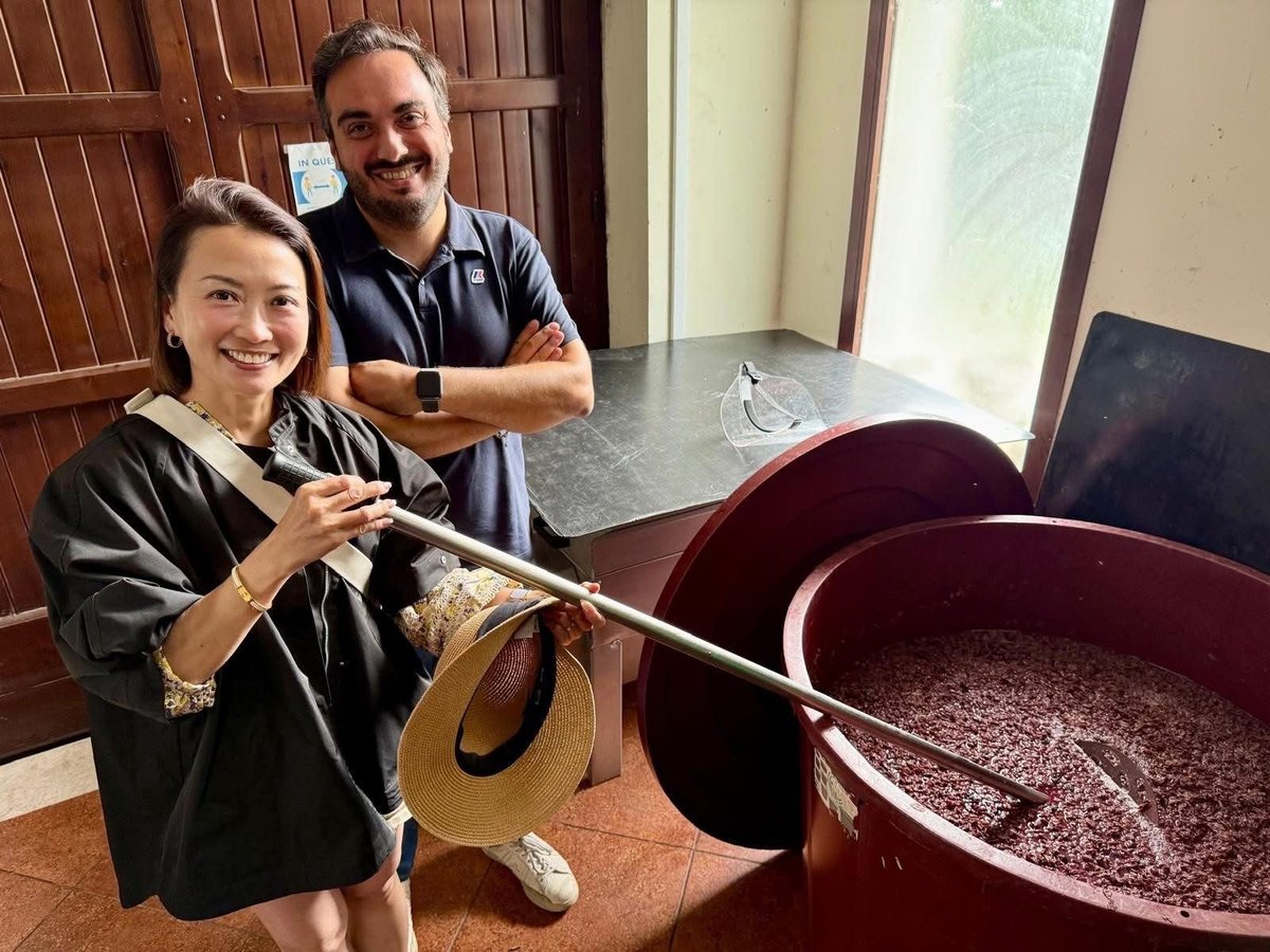 Two people demonstrating traditional coffee roasting with large red roasting pans and wooden implements