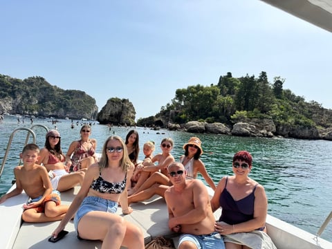 Group of people sitting on a boat in turquoise water with rocky islands and lush green vegetation in the background