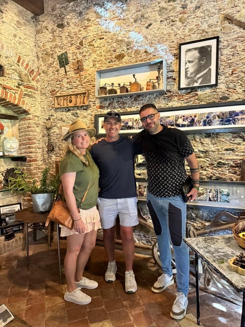 Three people posing together in a room with exposed brick walls, vintage photos, and Western memorabilia on display shelves