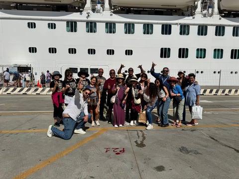 Large group of people posing together on a dock in front of a white cruise ship