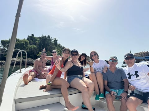 Group of people sitting together on a boat deck on a sunny day near the water
