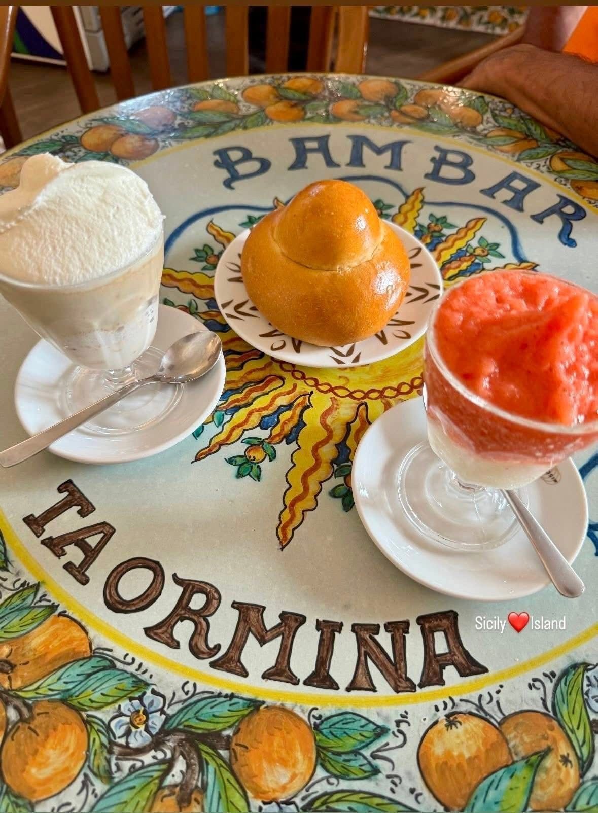 Three colorful desserts in glasses and a fresh orange on a decorative Palermo La Formina plate with lemon and orange fruit illustrations