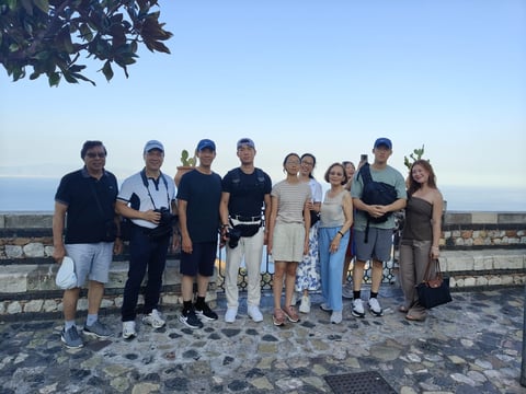 Group of people standing together on a scenic overlook with a cityscape and water visible in the background